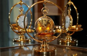 Goldene Taschenuhr in einem dekorativen St&auml;nder, reflektiert in einem Spiegel.